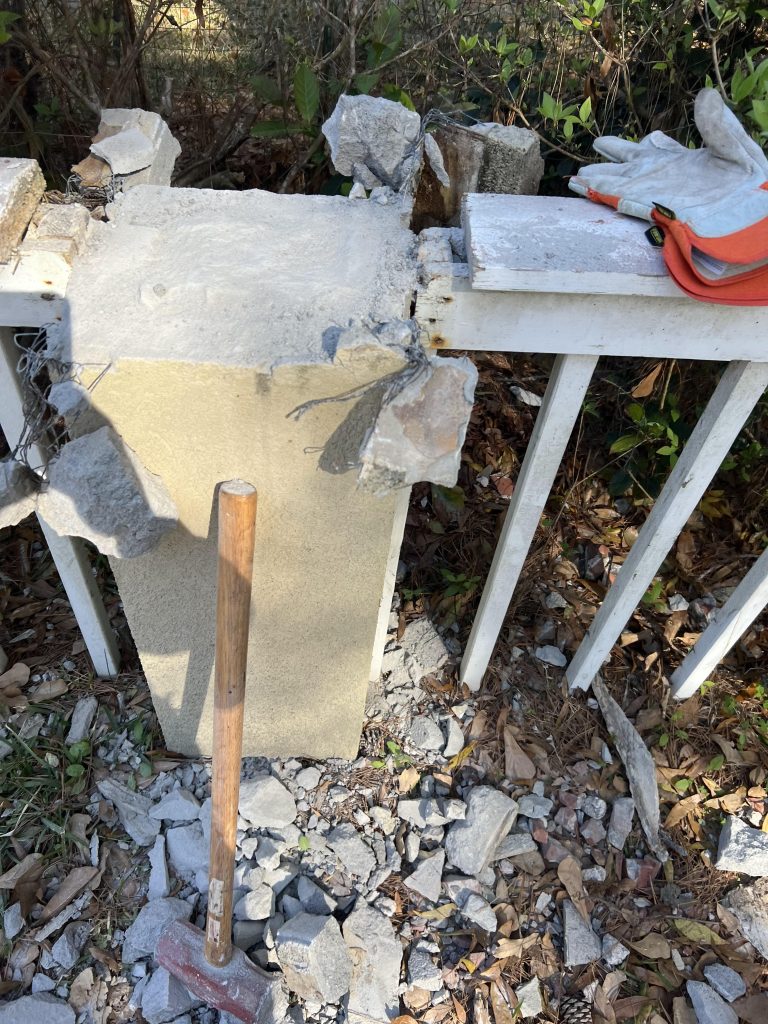 Worker dismantling an old concrete fence as part of a professional fence removal service.